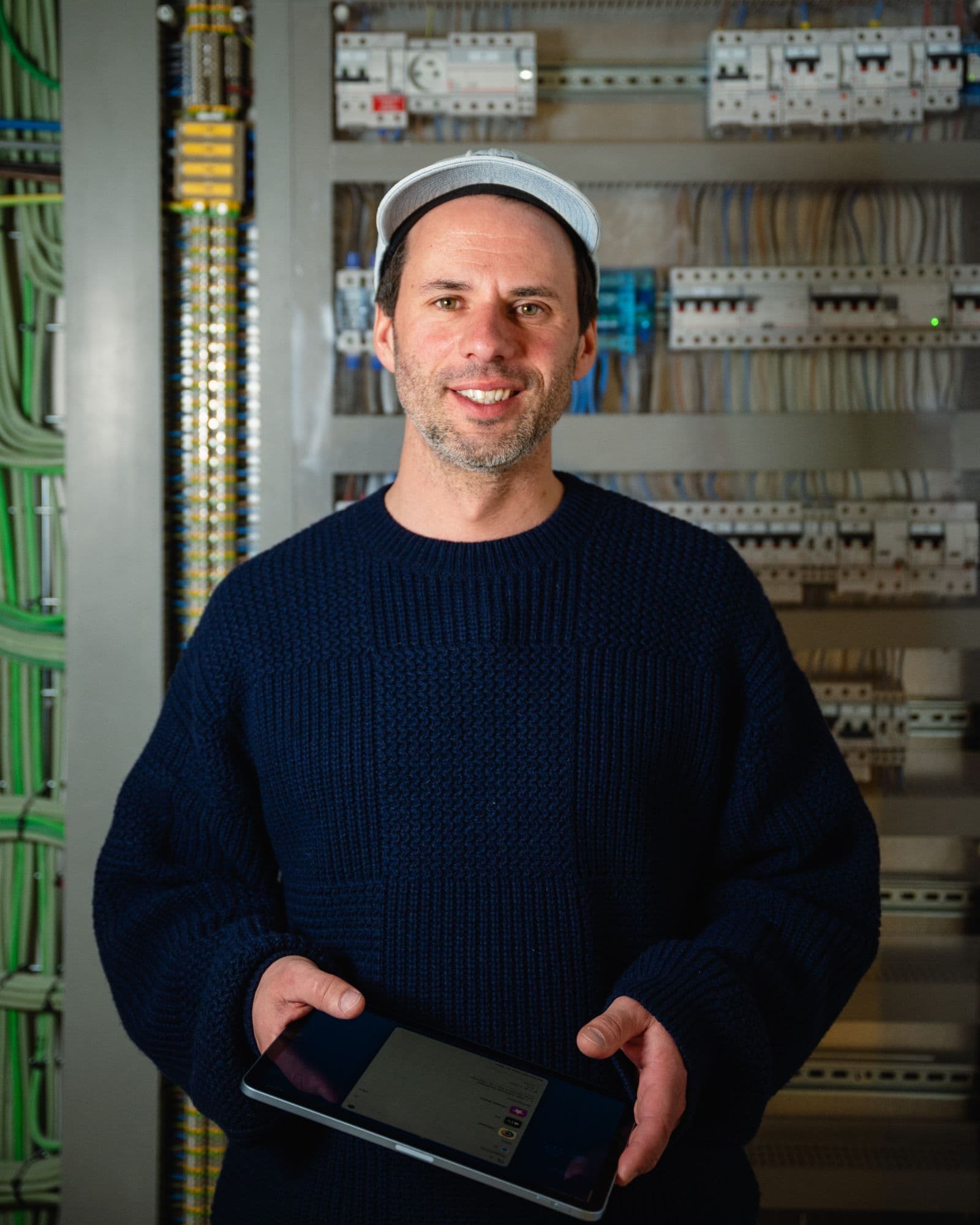 Ben, électricien chez ElectriCAD, devant un tableau électrique, tablette en main