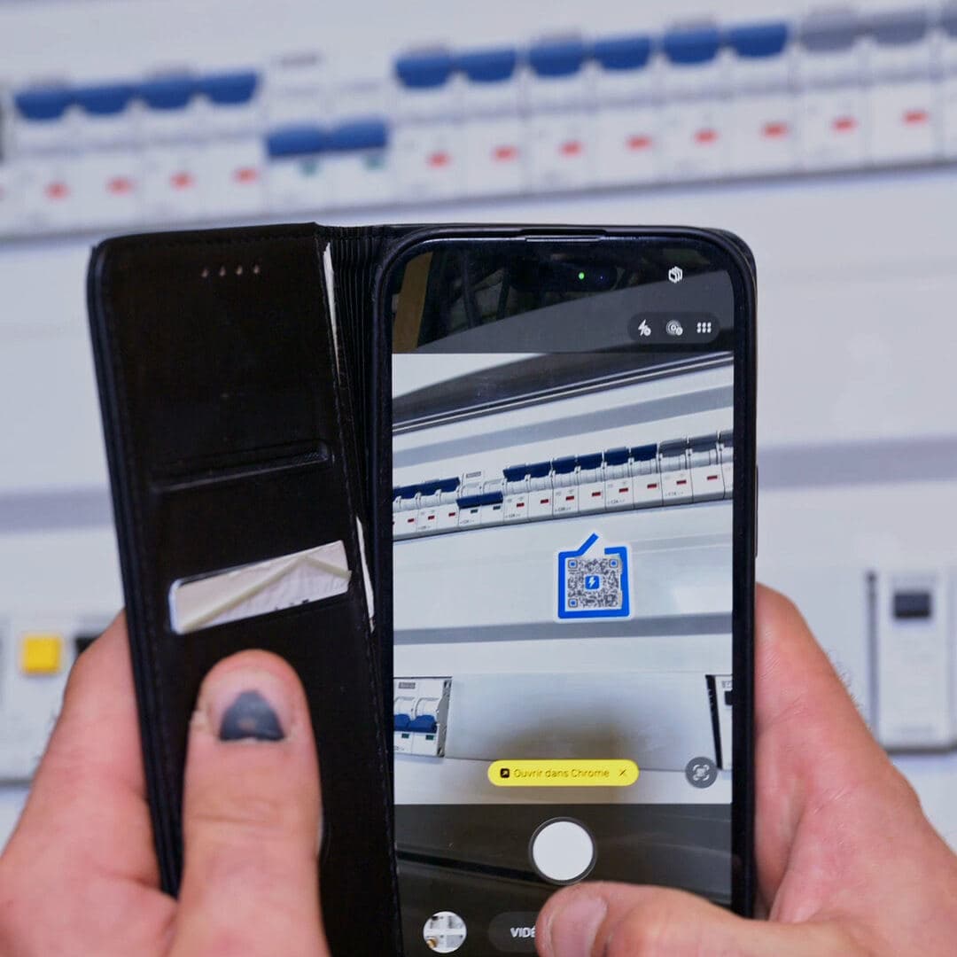 Un téléphone scanne le sticker d'un tableau électrique